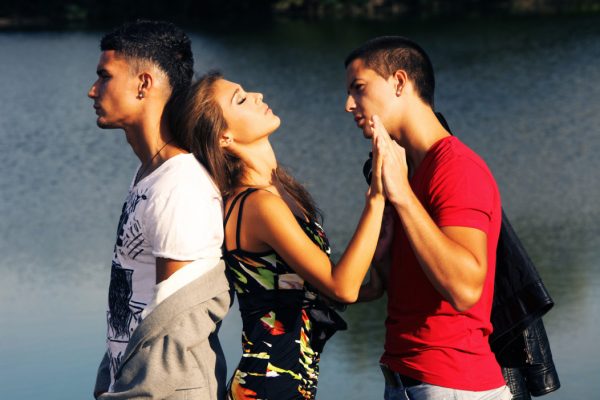 Love triangle, two young men and young woman on the beach at sunset